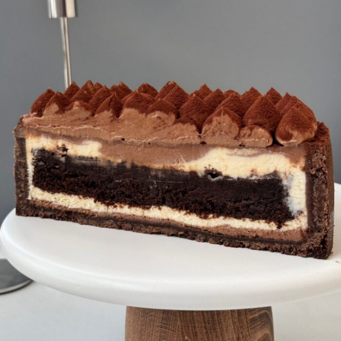 Sernik z warstwą brownie i czekoladowym kremem, posypany kakao