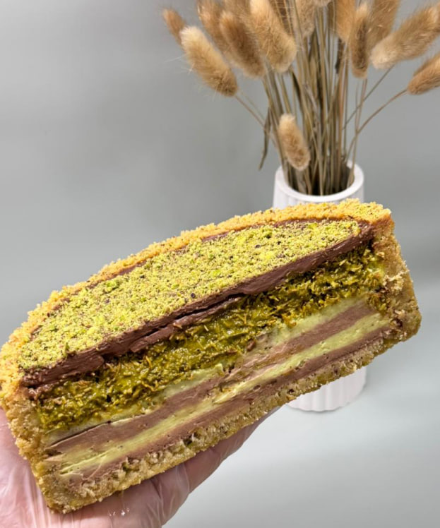 Przekrój luksusowego sernika z pistacjami, kataifi i mleczną czekoladą