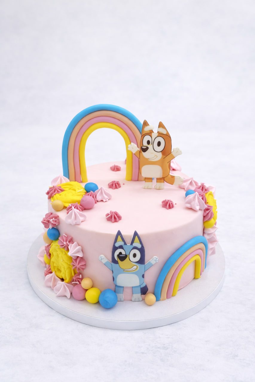 tort Bluey dla dzieci w pastelowym różu z tęczowymi dekoracjami i figurkami