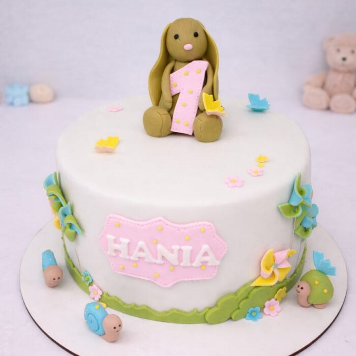 tort z króliczkiem trzymającym jedynkę, biały fondant, pastelowe kwiatki, tabliczka z imieniem Hania